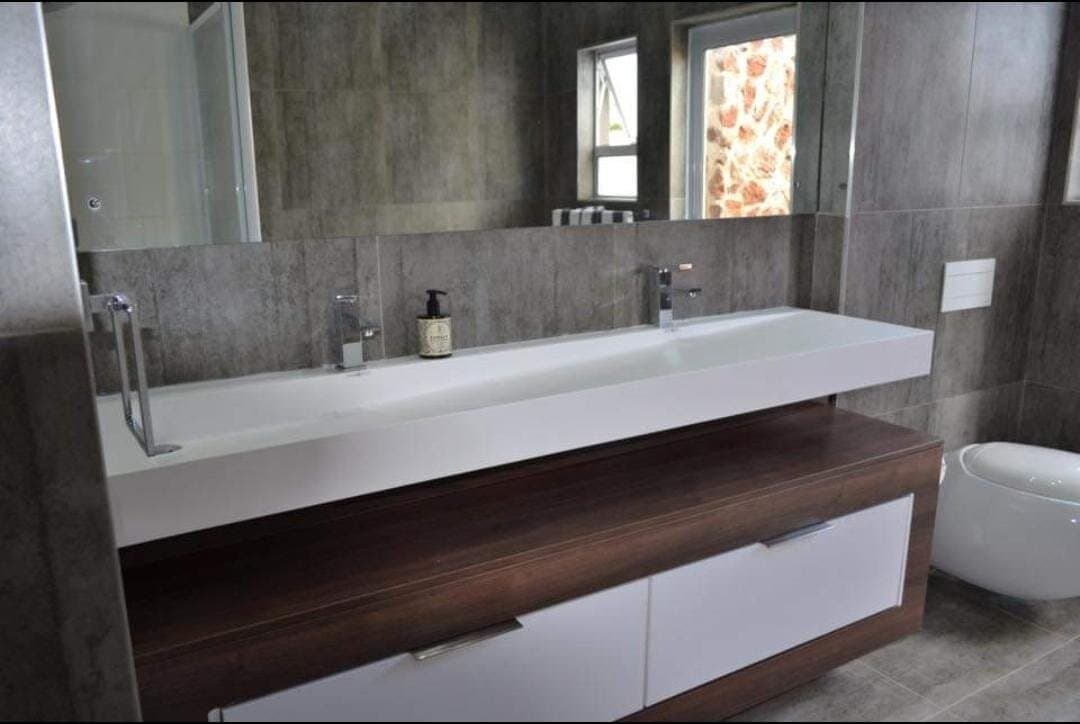 Bathroom renovation with a long trough-style double vanity and dark stone-look tile