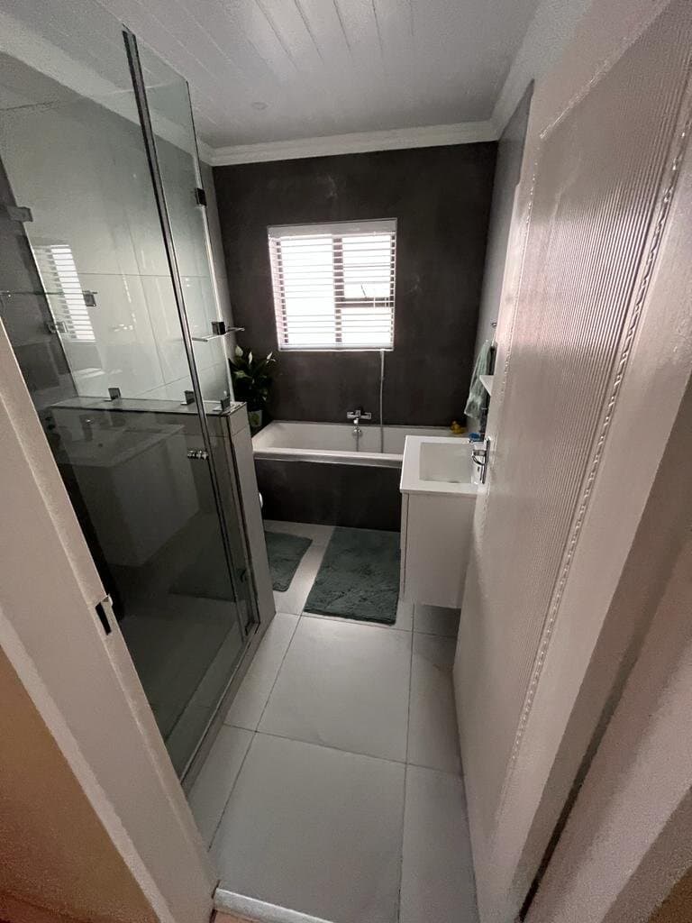 Bathroom renovation with a glass-enclosed shower, freestanding bath and dark feature wall