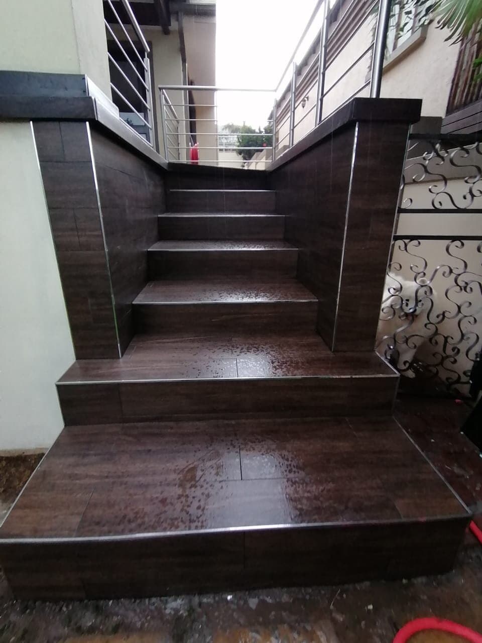 Outdoor tiled staircase with stainless steel balustrade leading up to a first-floor entrance
