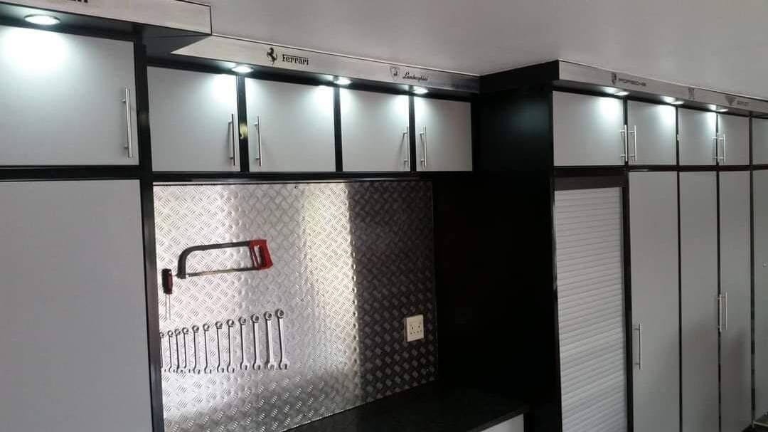 Garage fit-out with black cabinetry, brushed metal panelling and roller shutter storage