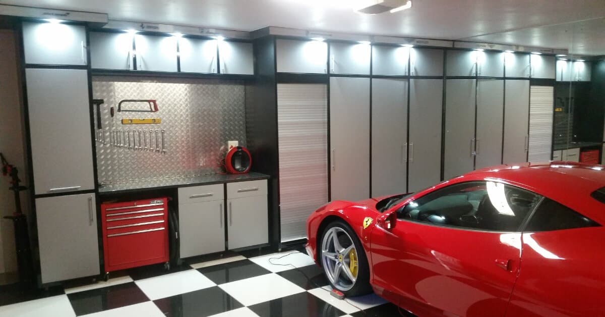 Garage fit-out with black and grey cabinetry, tool storage wall and checkerboard flooring