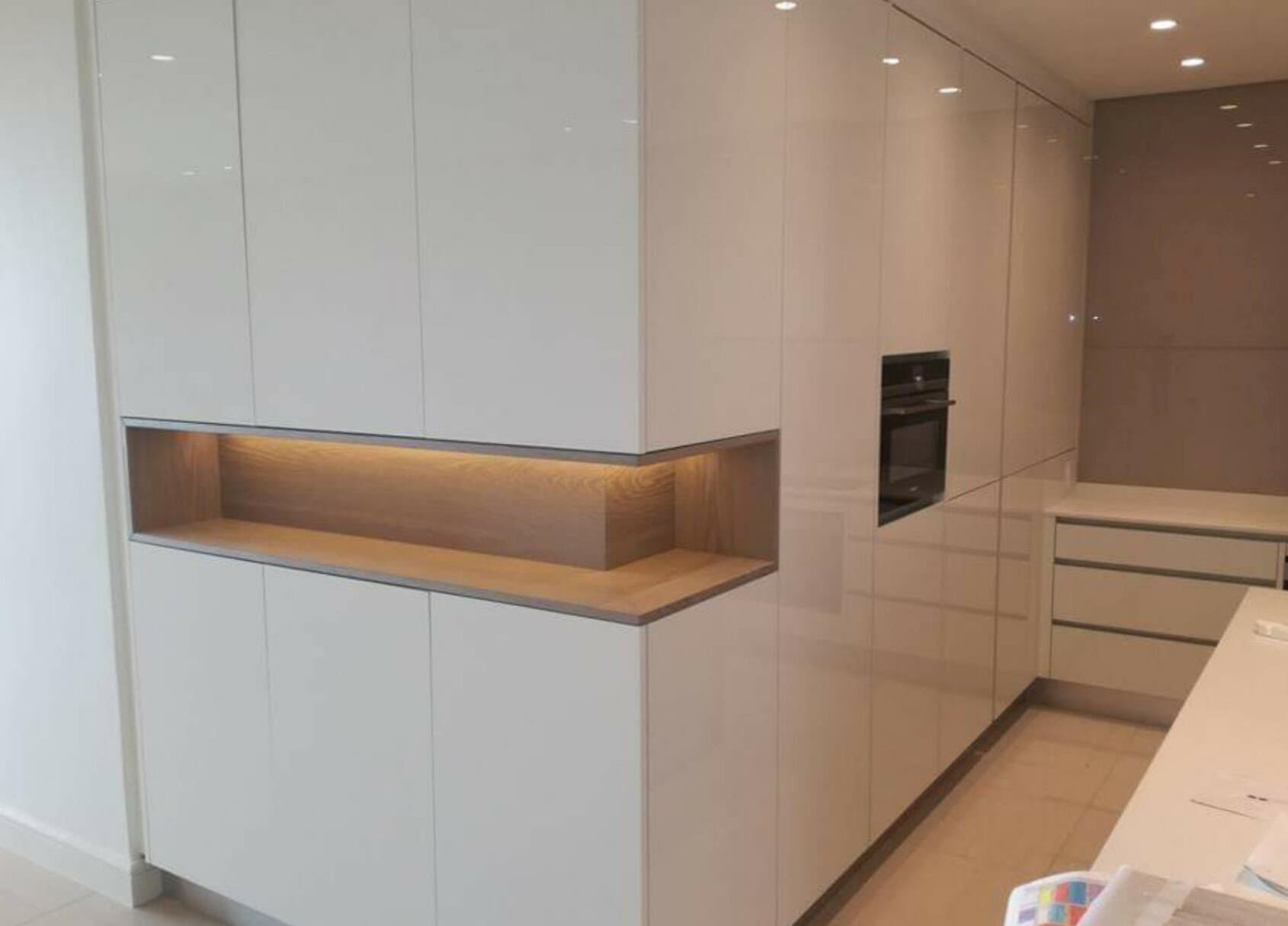 Kitchen renovation with high-gloss white cabinetry and a built-in lit display niche