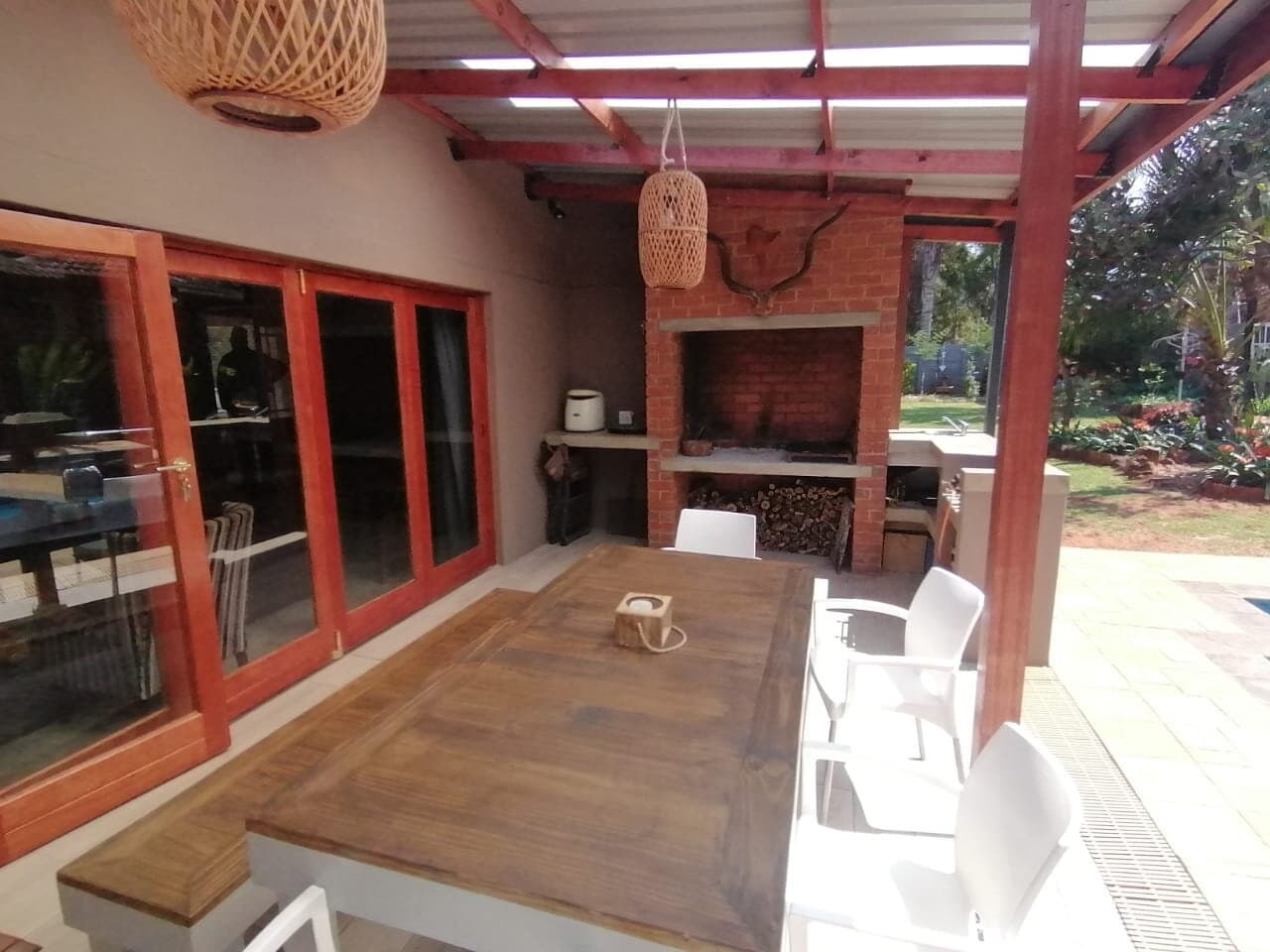 Timber pergola patio with a built-in brick braai and outdoor dining table