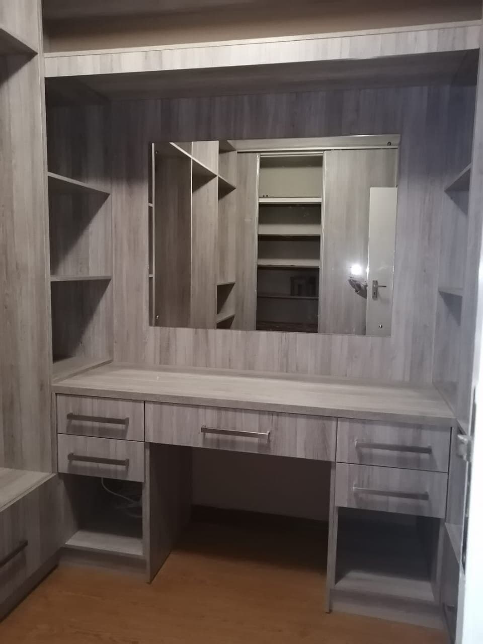 Built-in dressing table with mirror, open shelving and drawers in a walk-in closet